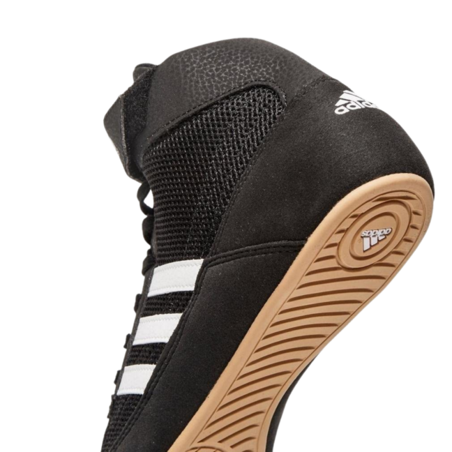 Black Adidas shoe with white stripes on a white background