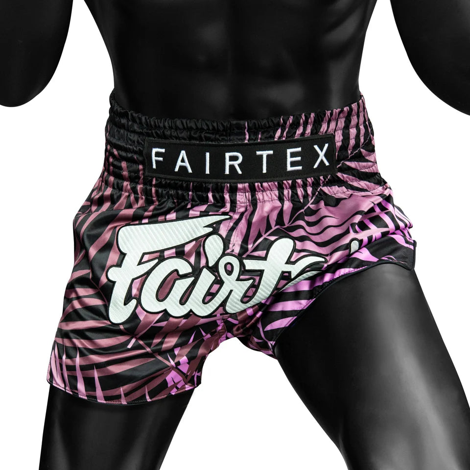 Pink and black patterned Fairtex shorts on a person against a white background