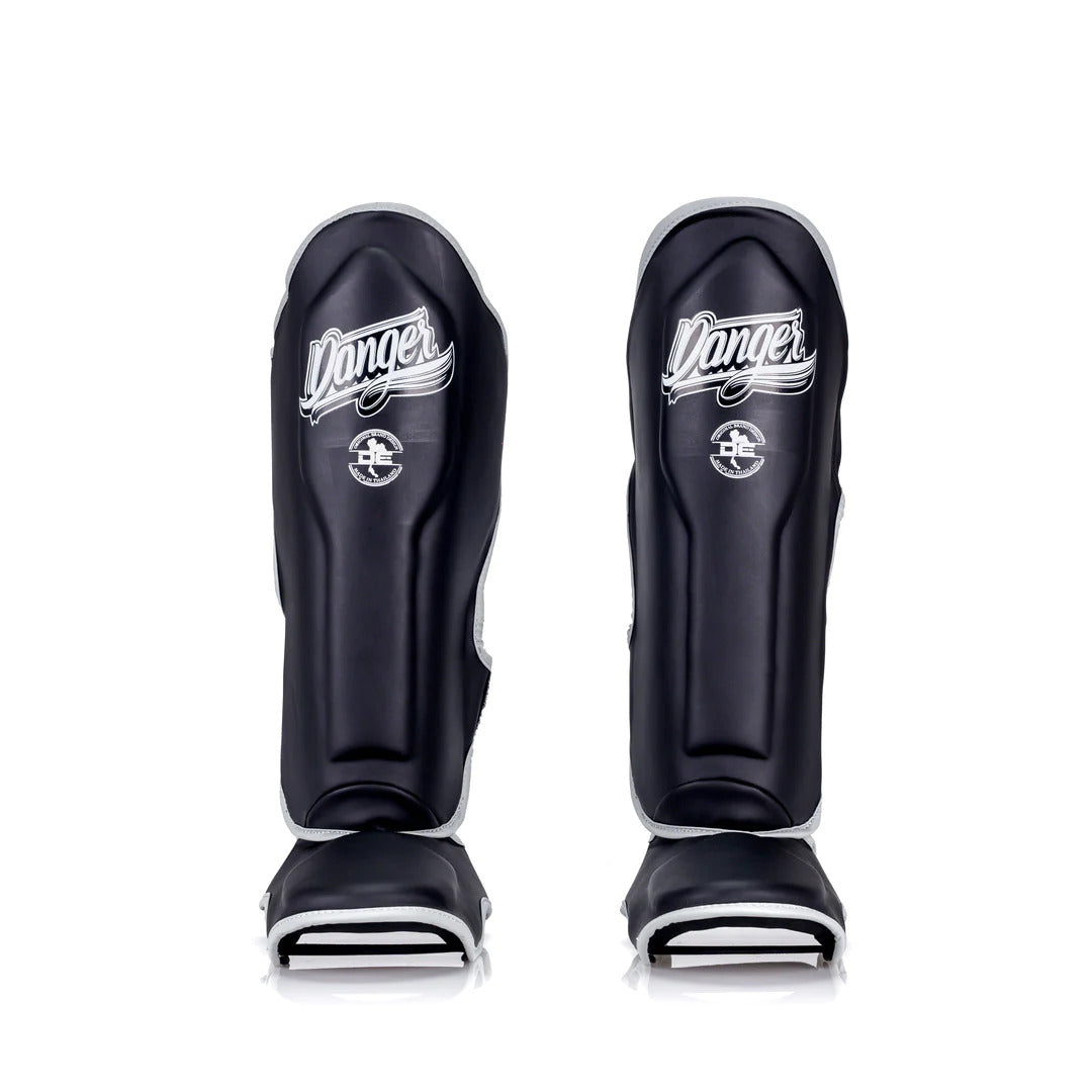 Pair of black shin guards with 'Danger' branding on a white background