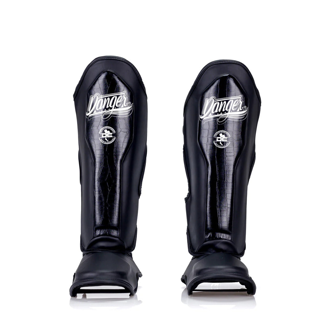 Pair of black shin guards with 'Danger' branding on a white background