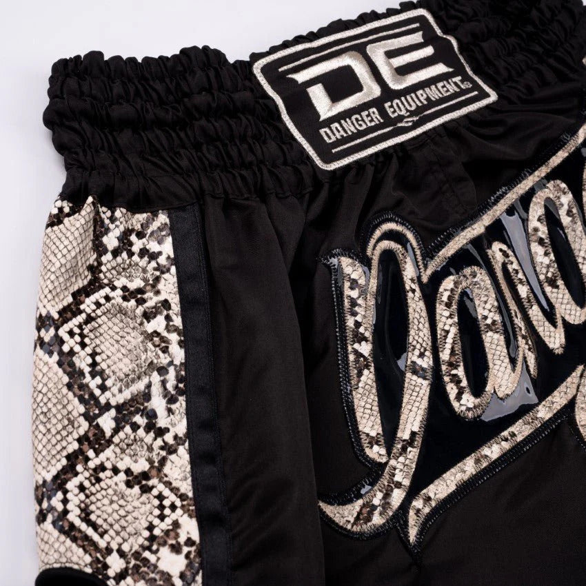 Black shorts with snake print and 'DE' logo on a white background