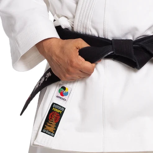 Male wearing a white martial arts uniform with a black belt and visible brand logos.