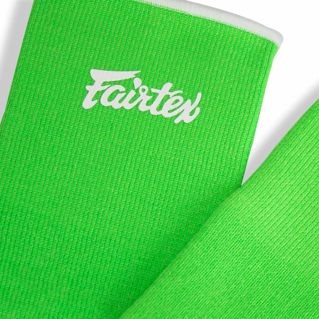 Two green Fairtex ankle guards on a white background