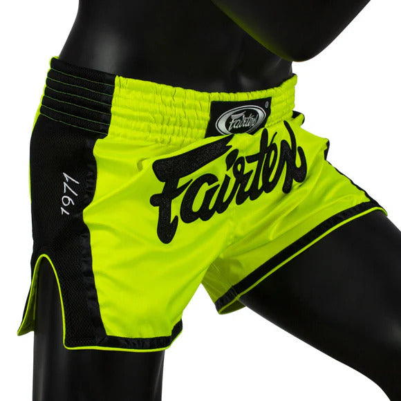 Neon green Muay Thai shorts with black accents and 'Fairtex' branding on a mannequin.