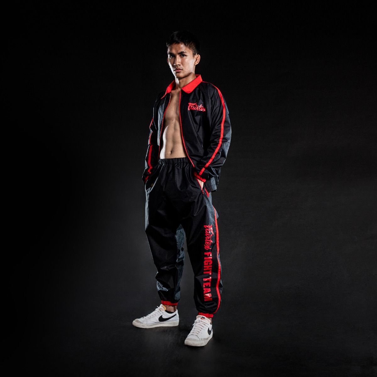 Person wearing a black and red Fairtex tracksuit with visible branding on a dark background
