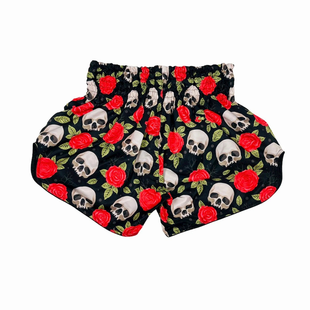 Muay Thai shorts with skull and rose pattern on a black background