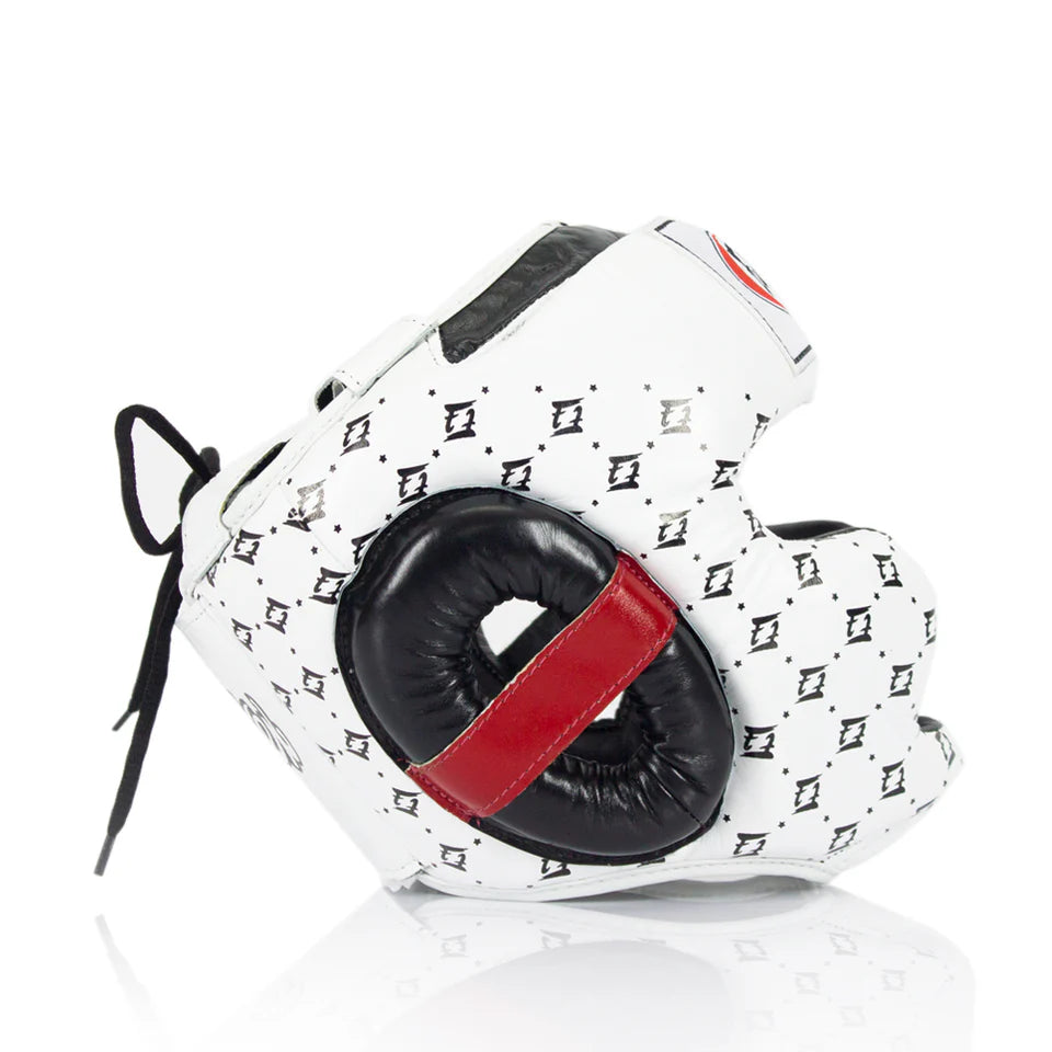 Side profile of a white Fairtex boxing headgear with black and red accents on a white background