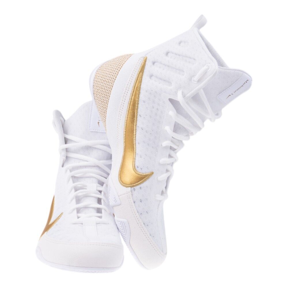 White Nike boxing sneakers with gold accents on a white background