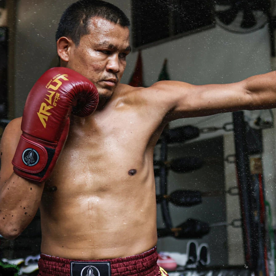 Seksan in red Arwut gloves and thai shorts with a blurred background