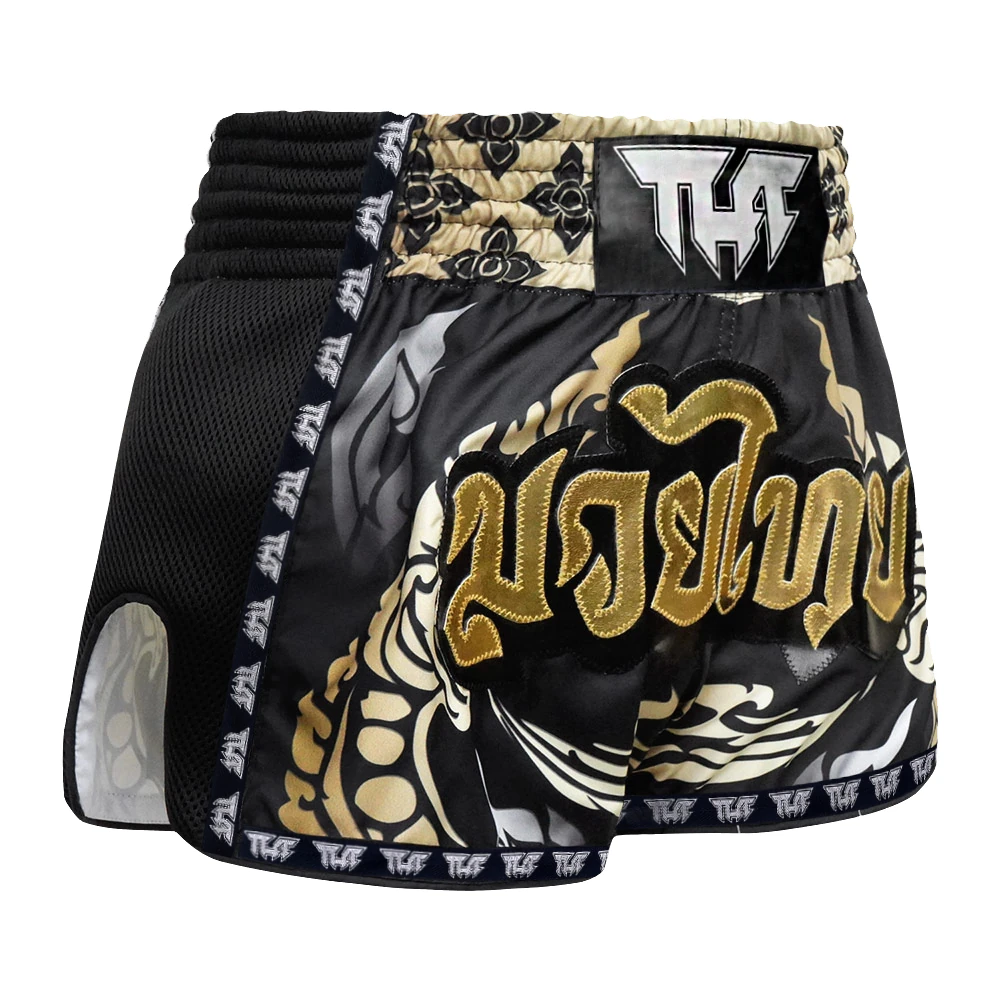 Black and gold Muay Thai shorts with intricate designs on a white background