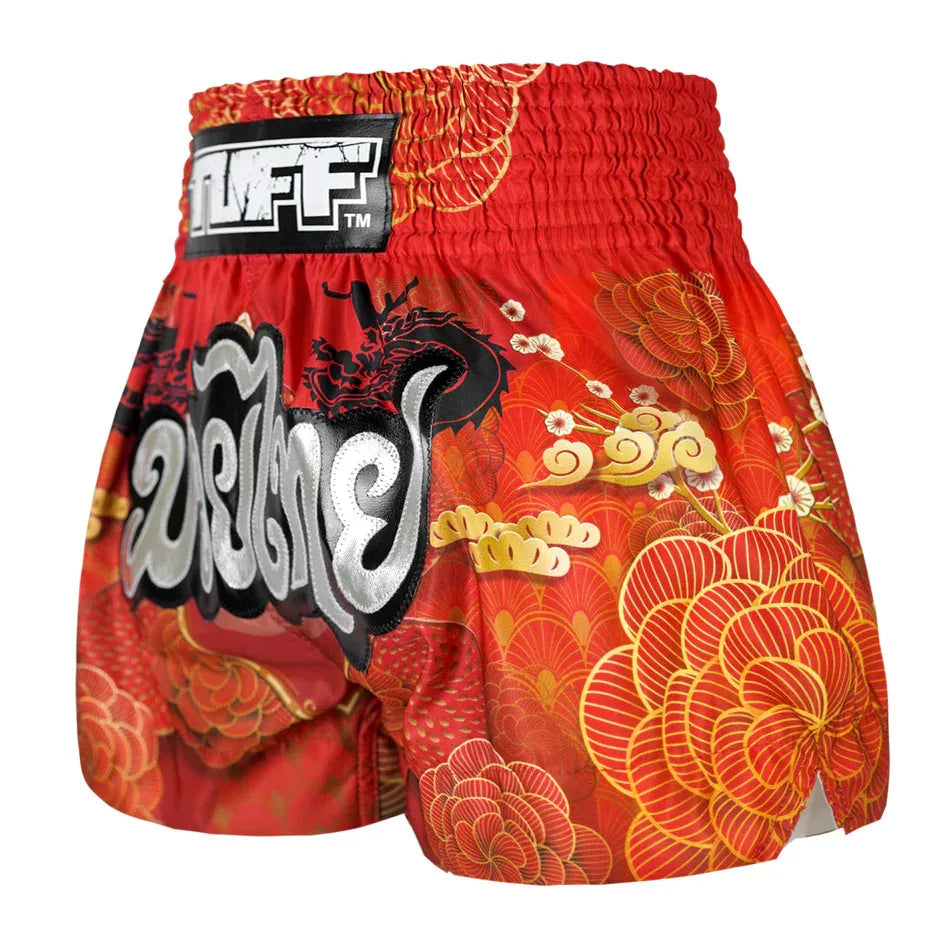 Red and orange floral-patterned Muay Thai shorts with a prominent brand logo on a white background