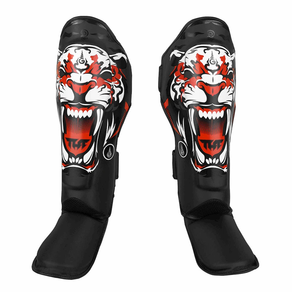 Pair of black shin guards with a tiger design on a white background
