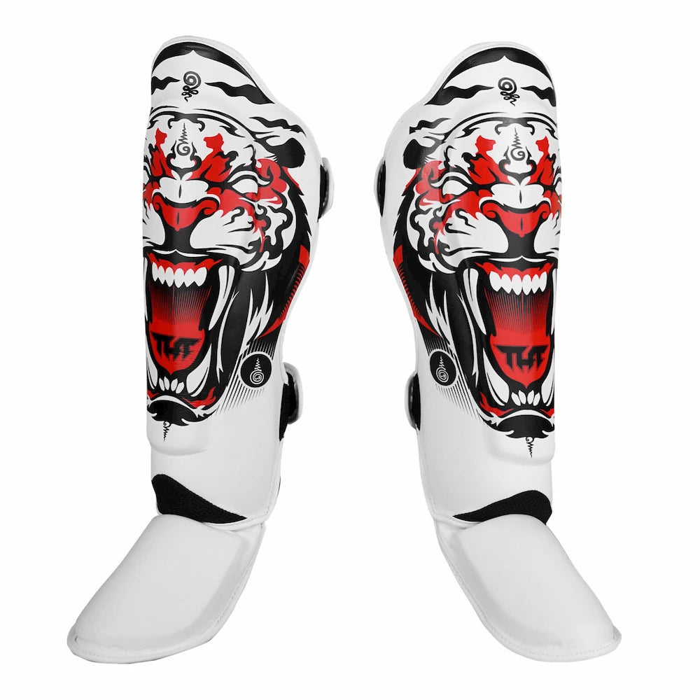 Pair of white Muay Thai shin guards with tiger design on a white background