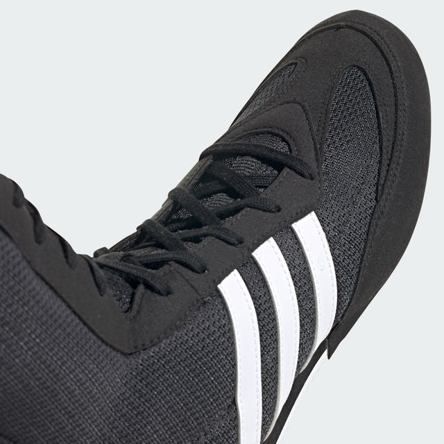 Black boxing shoe with white stripes on a light gray background