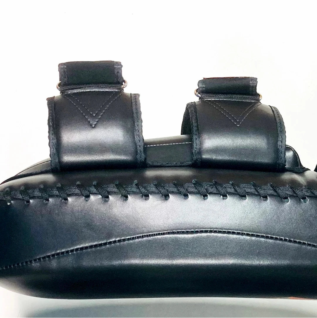 Close-up of a black leather Thai Pad with stitching details on a white background