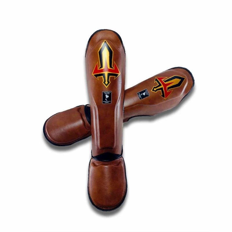 Pair of brown leather Arwut shin guards with a logo on a white background