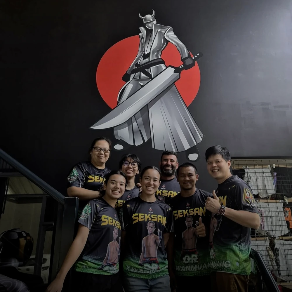 Group of people posing in front of a mural with a character holding a large sword.