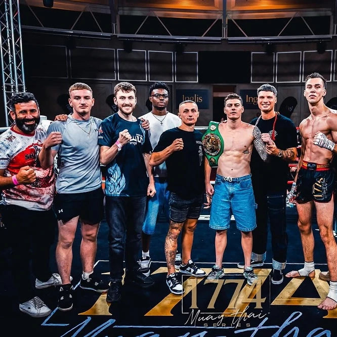 Group of men posing with a championship belt on a stage with '1774' branding.