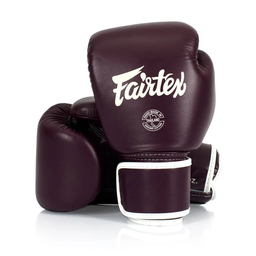 Pair of maroon boxing gloves with 'Fairtex' branding on a white background
