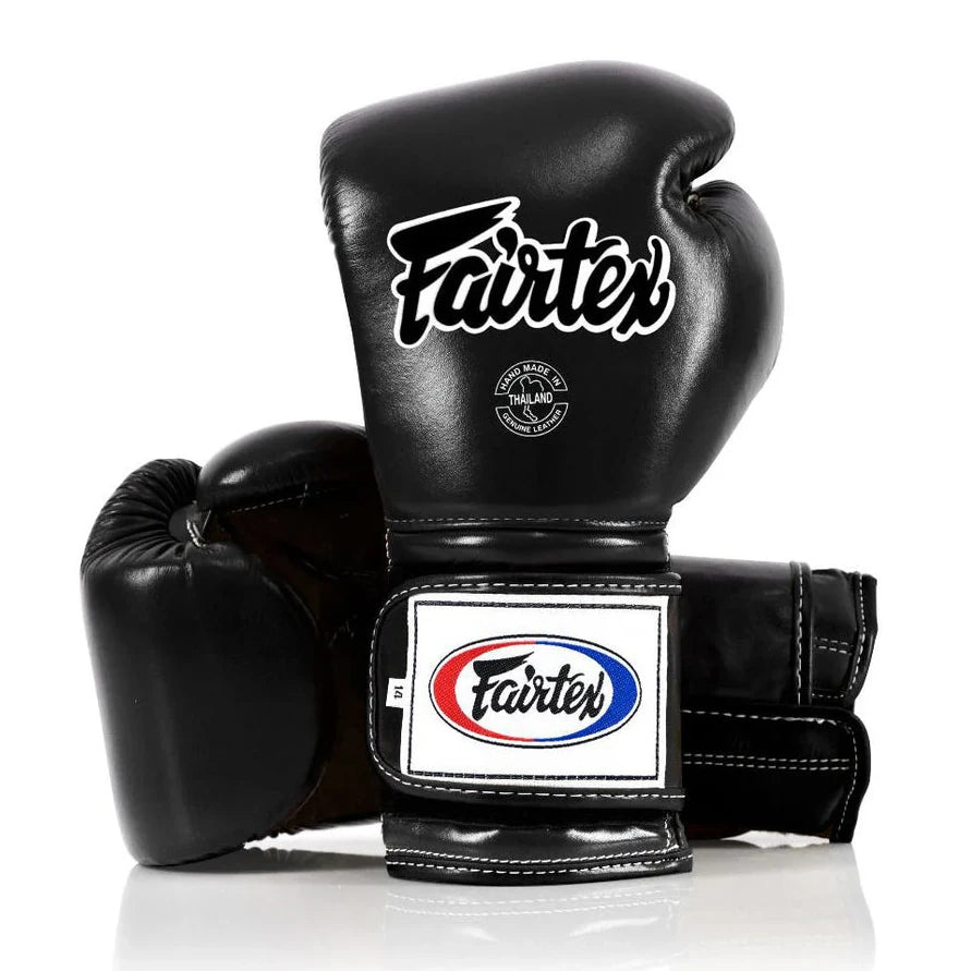 Black Fairtex boxing gloves on a white background