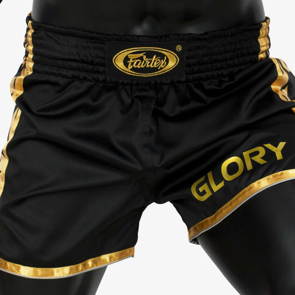 Black and gold Thai boxing shorts with 'Fairtex' branding on a white background