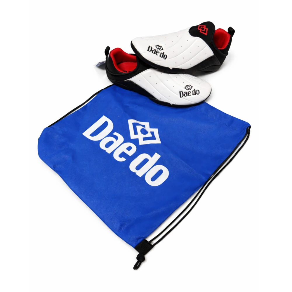 Pair of white and black shoes with red accents on a blue drawstring bag featuring 'Dae do' branding.