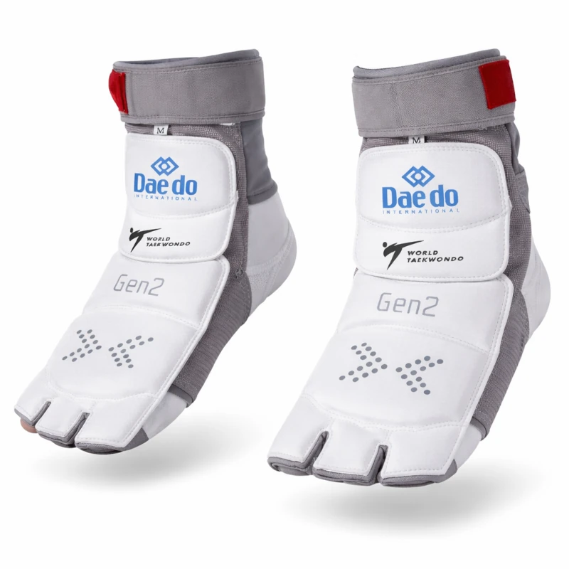 Pair of white and gray taekwondo foot guards with 'Dae do' branding on a white background.