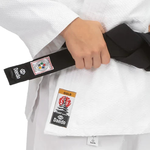 Person wearing a white martial arts uniform with a black belt featuring Daedo branding.
