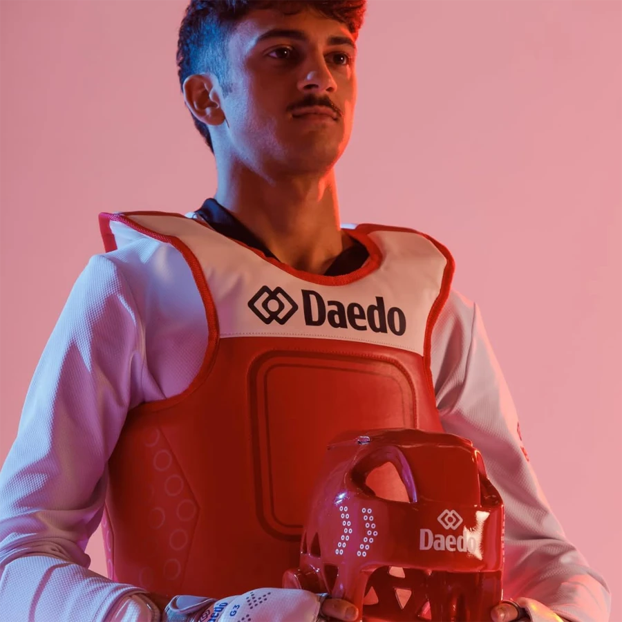 Person wearing a red and white protective vest with 'Daedo' branding against a pink background