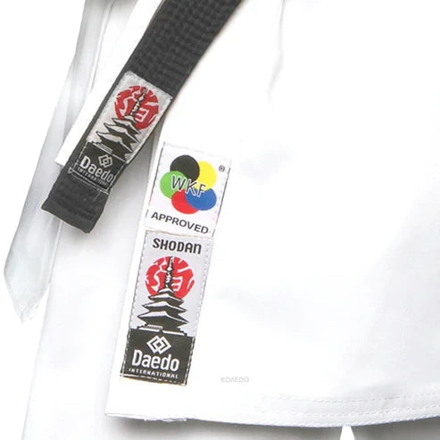 Close-up of a martial arts uniform with a black belt and 'Daedo' label on a white background