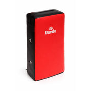 Red and black rectangular kick pad with 'Daedo' logo on a white background
