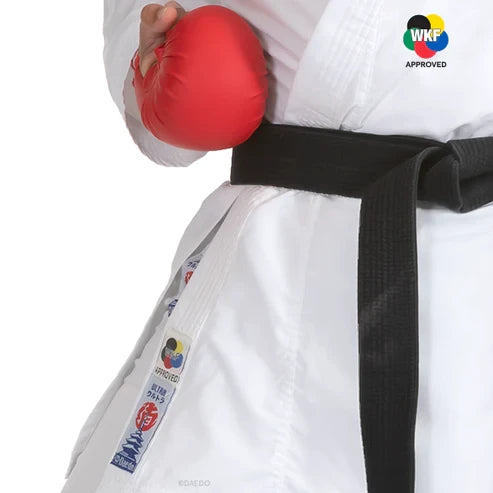 Male in a white martial arts uniform with a black belt holding a red punching bag, WKF Approved logo visible.