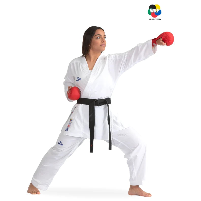 Woman in a white martial arts uniform with red gloves and black belt, posing on a white background with WKF logo.