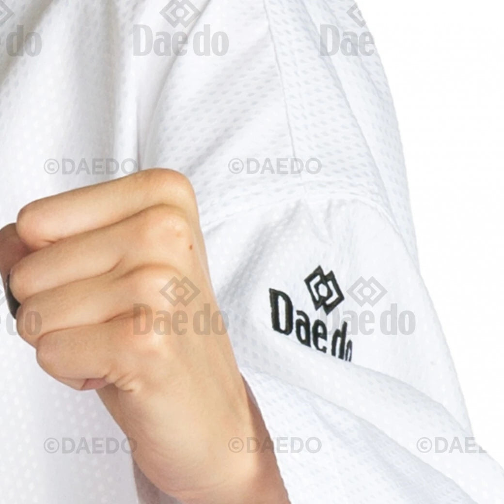 Close-up of a person wearing a white martial arts uniform with 'Daedo' branding.