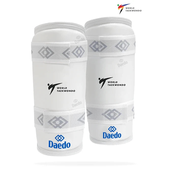 Pair of white shin guards with World Taekwondo and Daedo branding on a white background