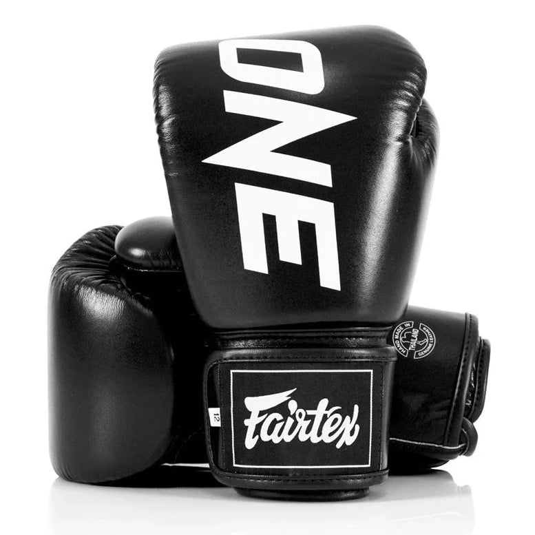 Black boxing gloves with 'ONE' and 'Fairtex' branding on a white background