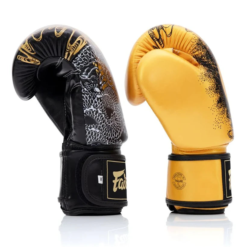 Pair of black and gold boxing gloves with intricate designs on a white background