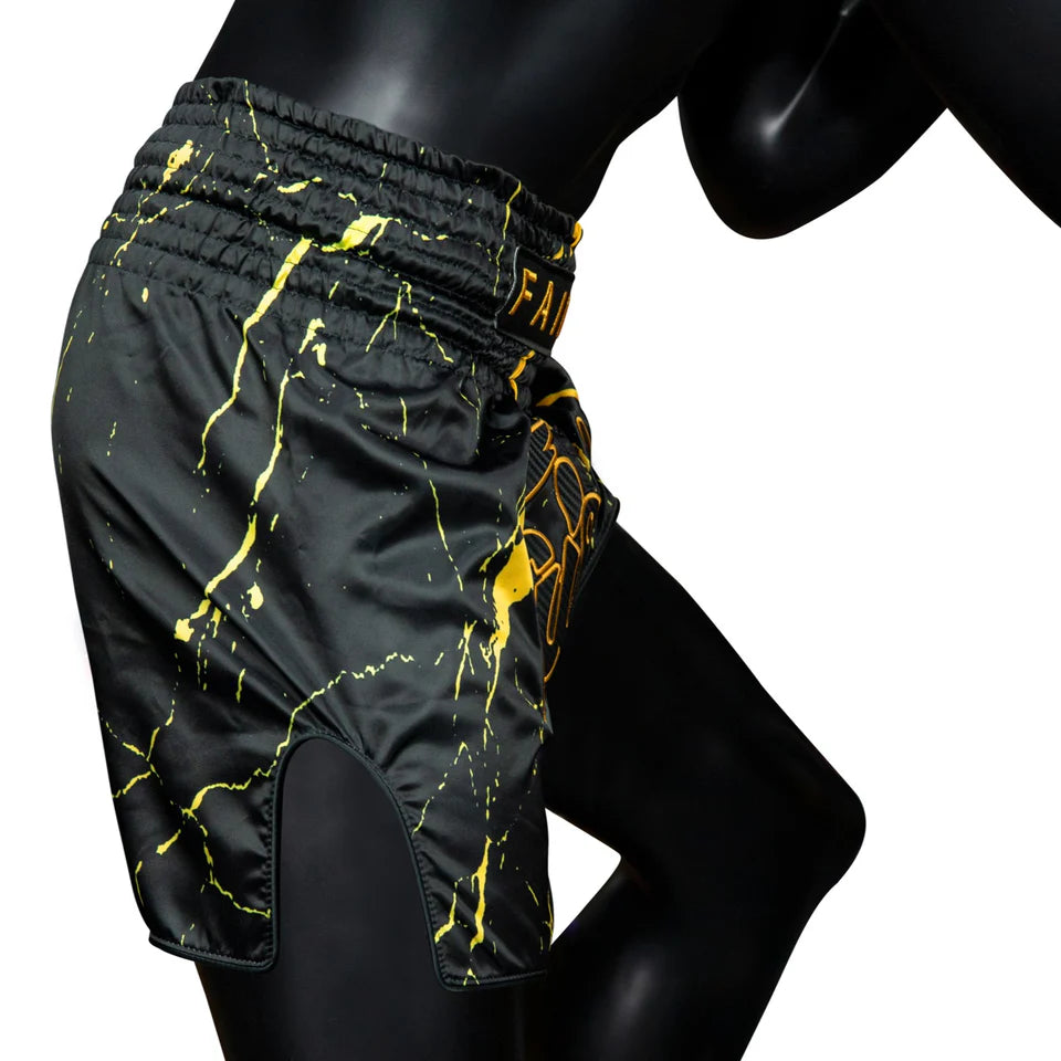 Black Muay Thai shorts with yellow abstract patterns on a mannequin against a white background
