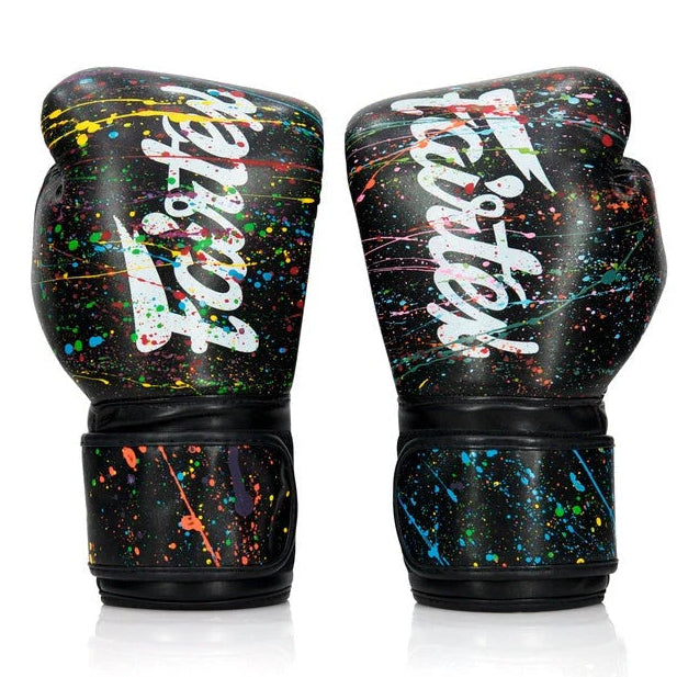 Pair of black boxing gloves with colorful splatter design and 'Fairtex' branding on a white background