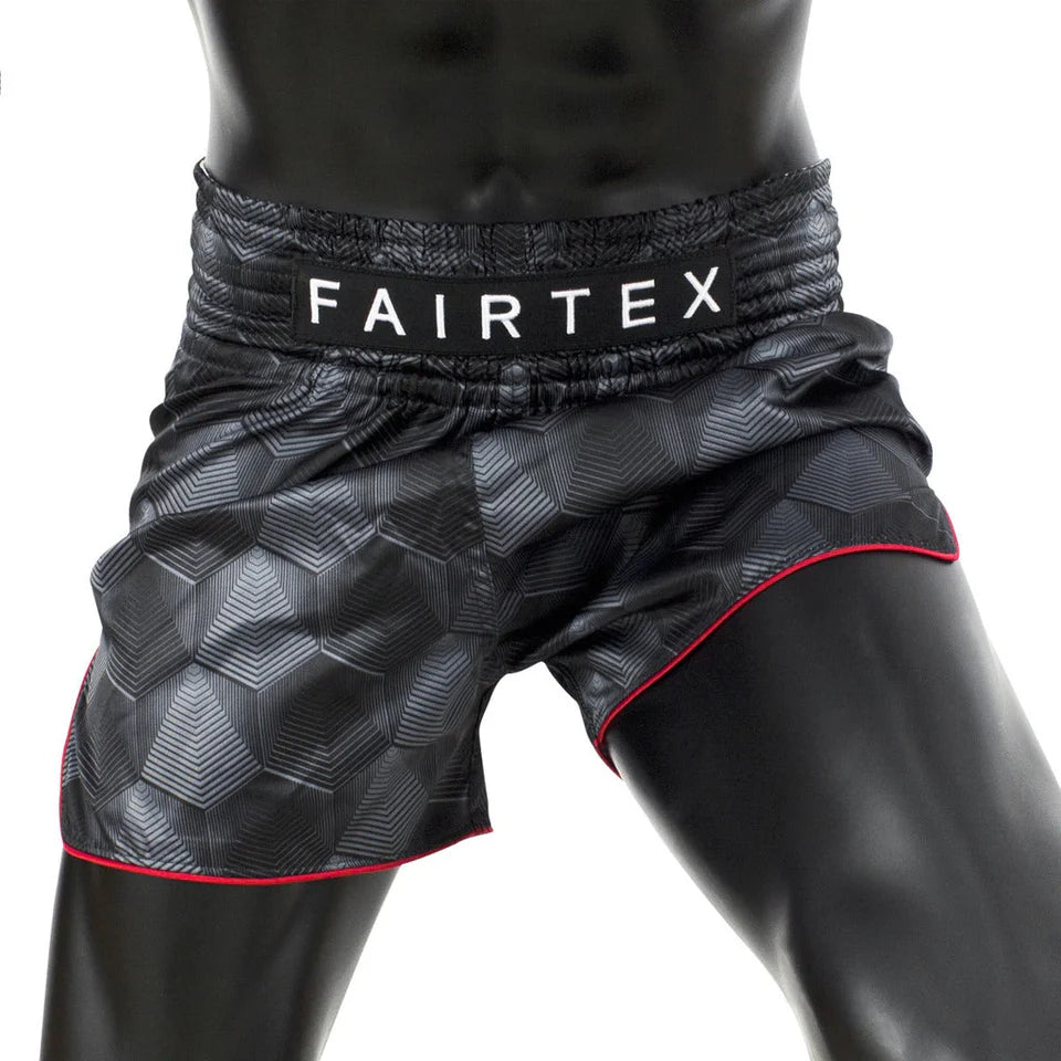 Black Muay Thai shorts with red trim featuring Fairtex branding on a white background