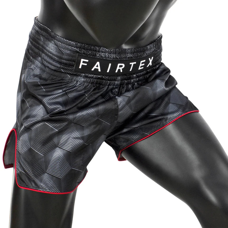 Black patterned Muay Thai shorts with 'Fairtex' branding on a mannequin.