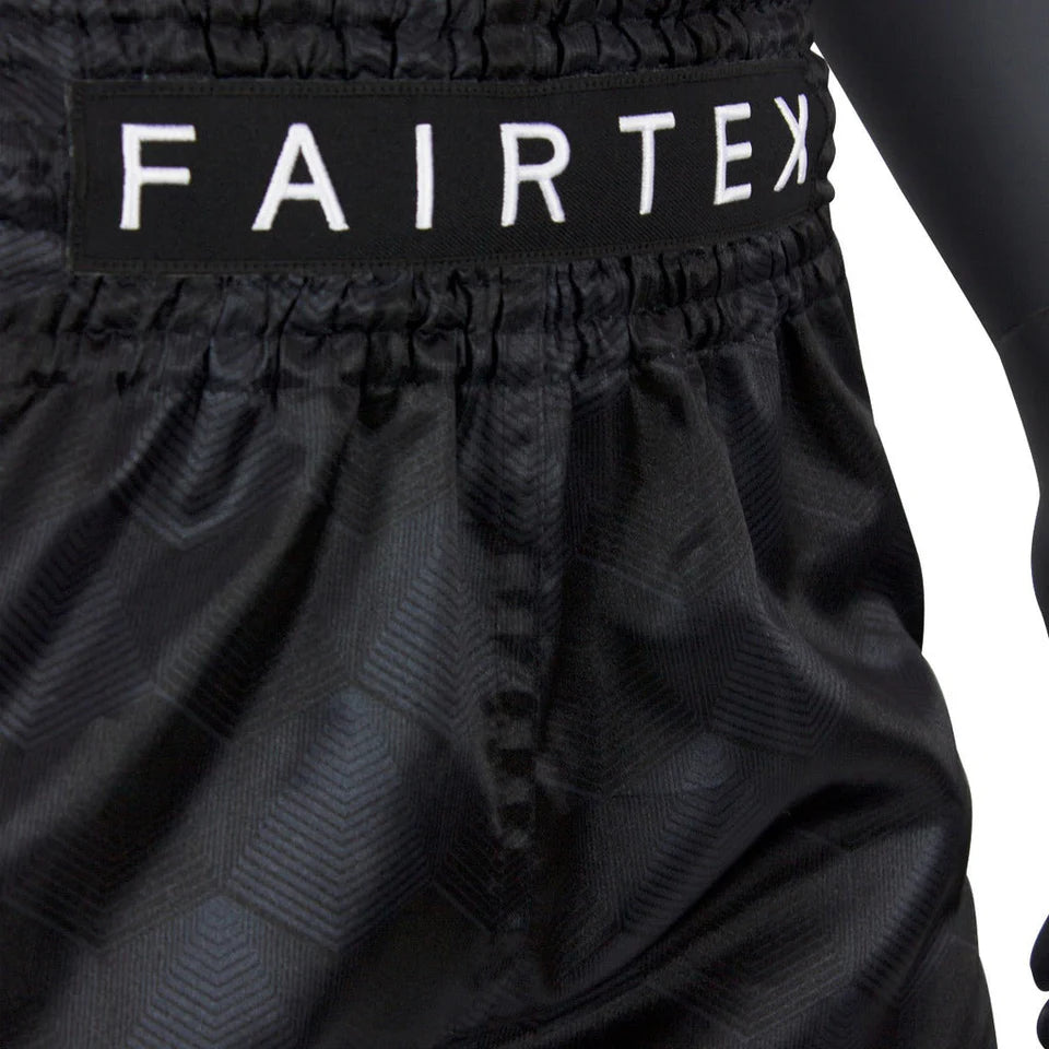Black Muay Thai shorts with 'FAIRTEX' branding on a white background