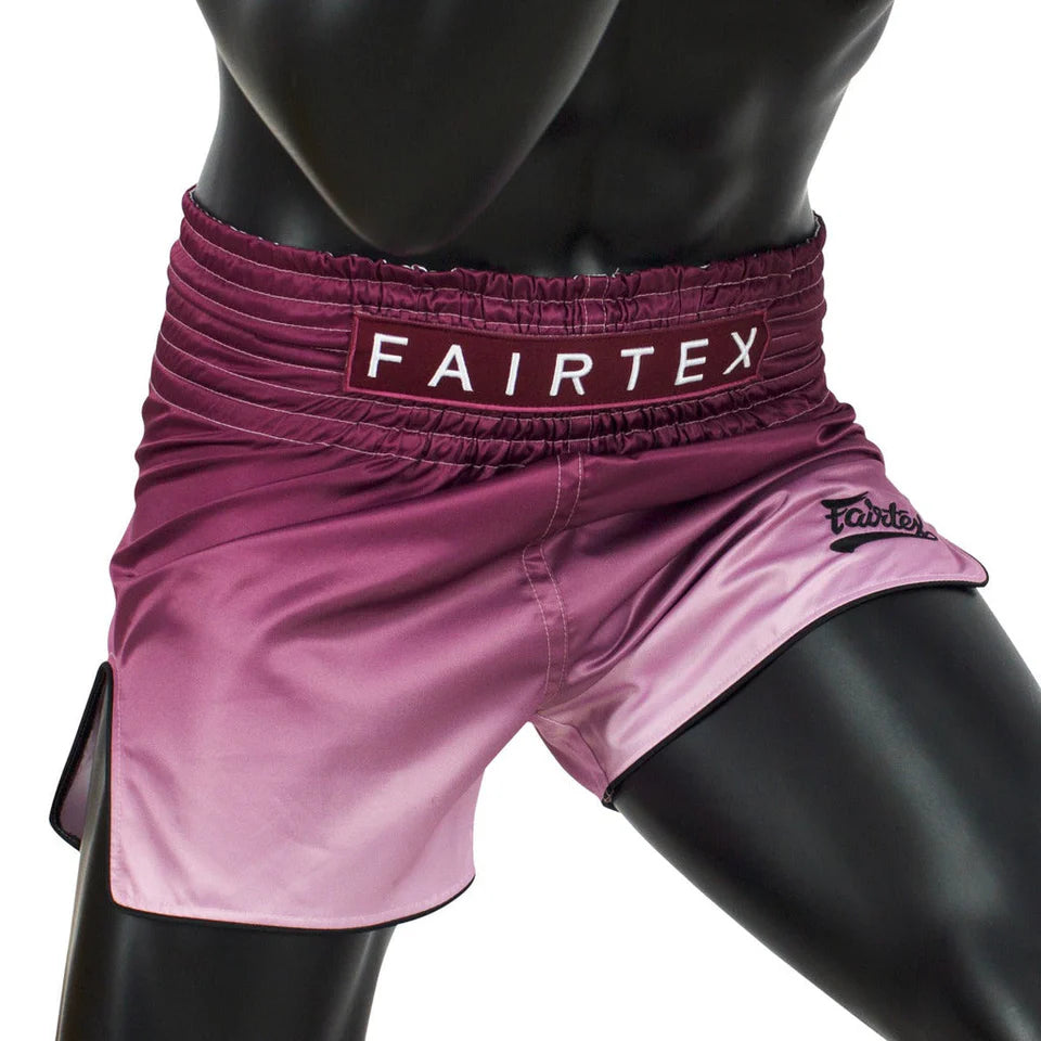 Pink Muay Thai shorts with Fairtex branding on a black mannequin.