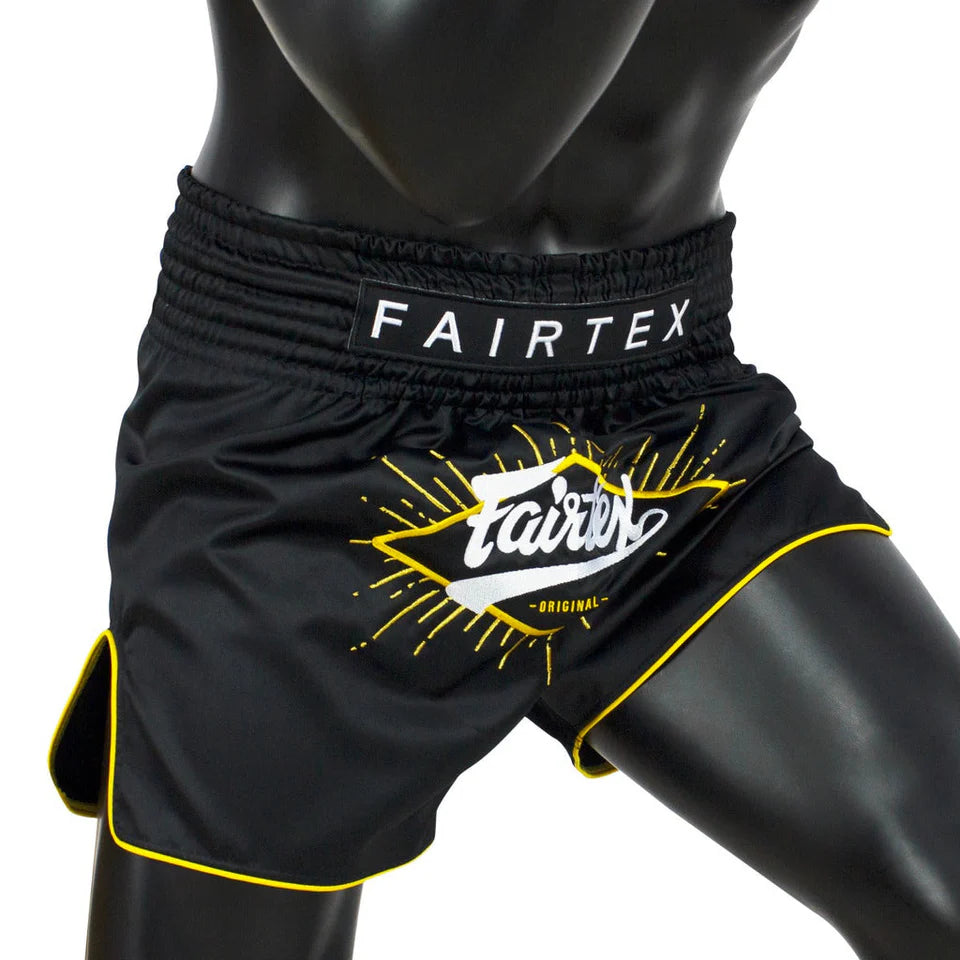 Black Fairtex shorts with yellow accents on a mannequin against a white background