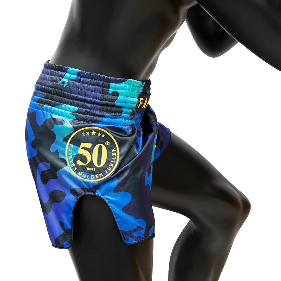 Blue camouflage Muay Thai shorts with a gold emblem on a mannequin against a white background