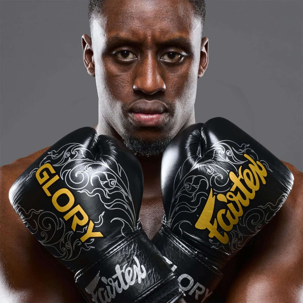 Boxer wearing black boxing gloves with 'Glory' and 'Fairtex' branding on a gray background