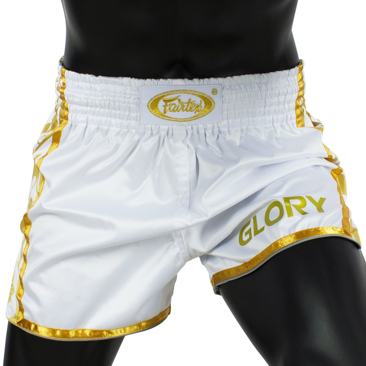 White boxing shorts with gold accents and 'Fairtex' branding
