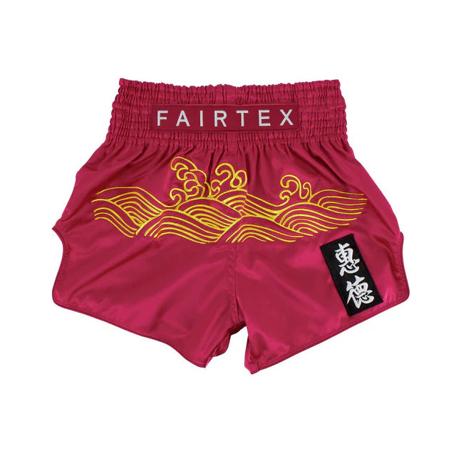 Red Fairtex Muay Thai shorts with yellow wave design on a white background