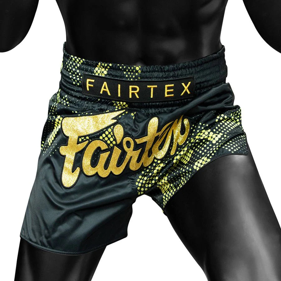Black and gold Fairtex shorts on a person against a white background