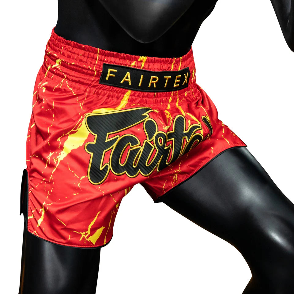 Red and yellow boxing shorts with 'Fairtex' branding on a black background
